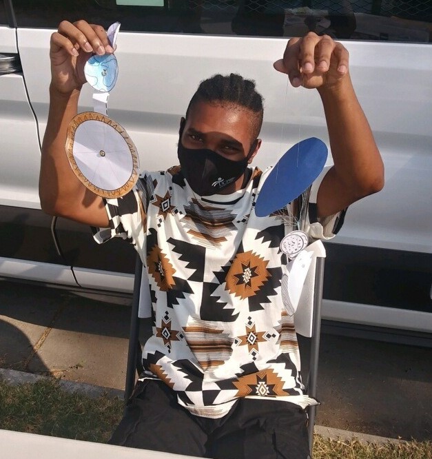 Student wearing mask holding up solar system craft